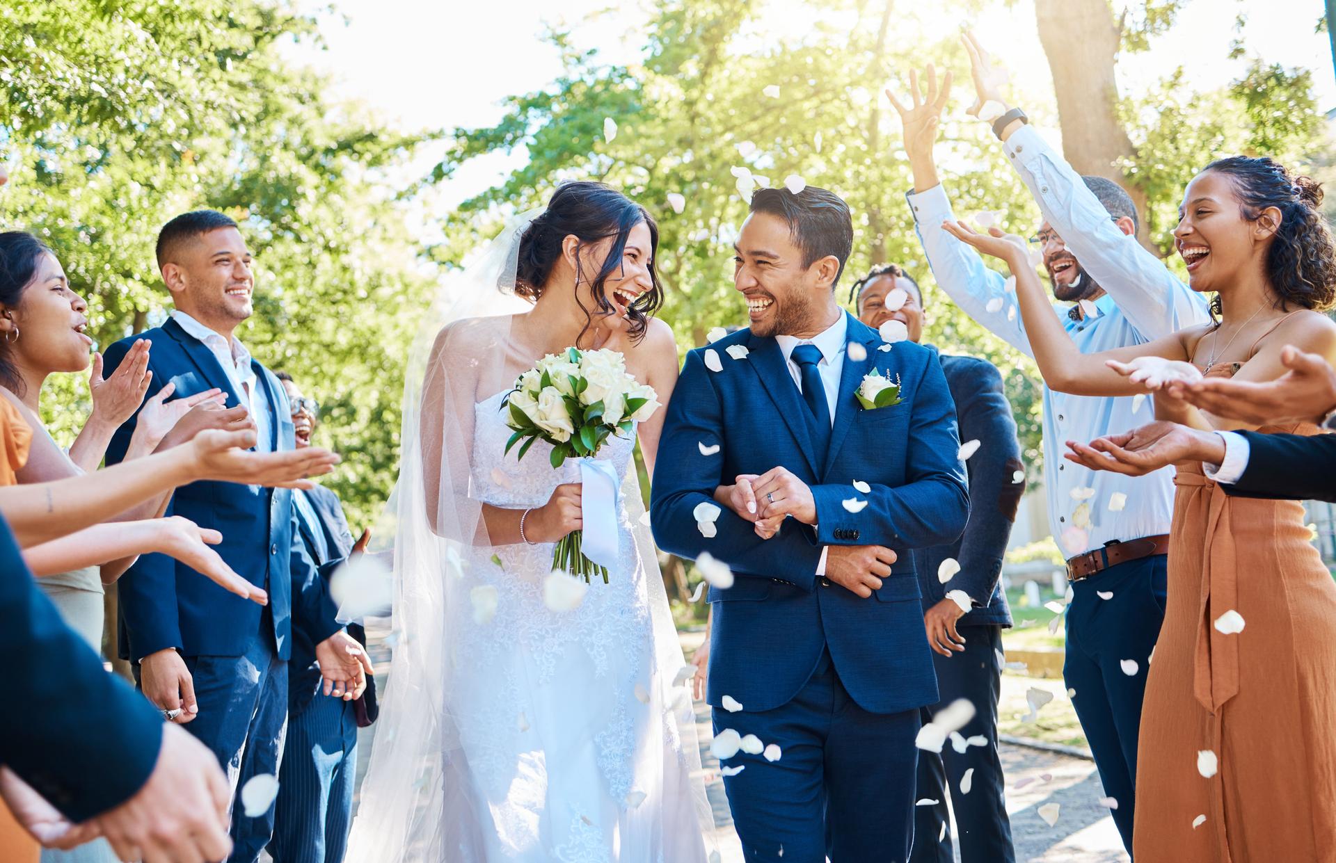 Wedding guests throwing confetti on newly wed bride and groom
